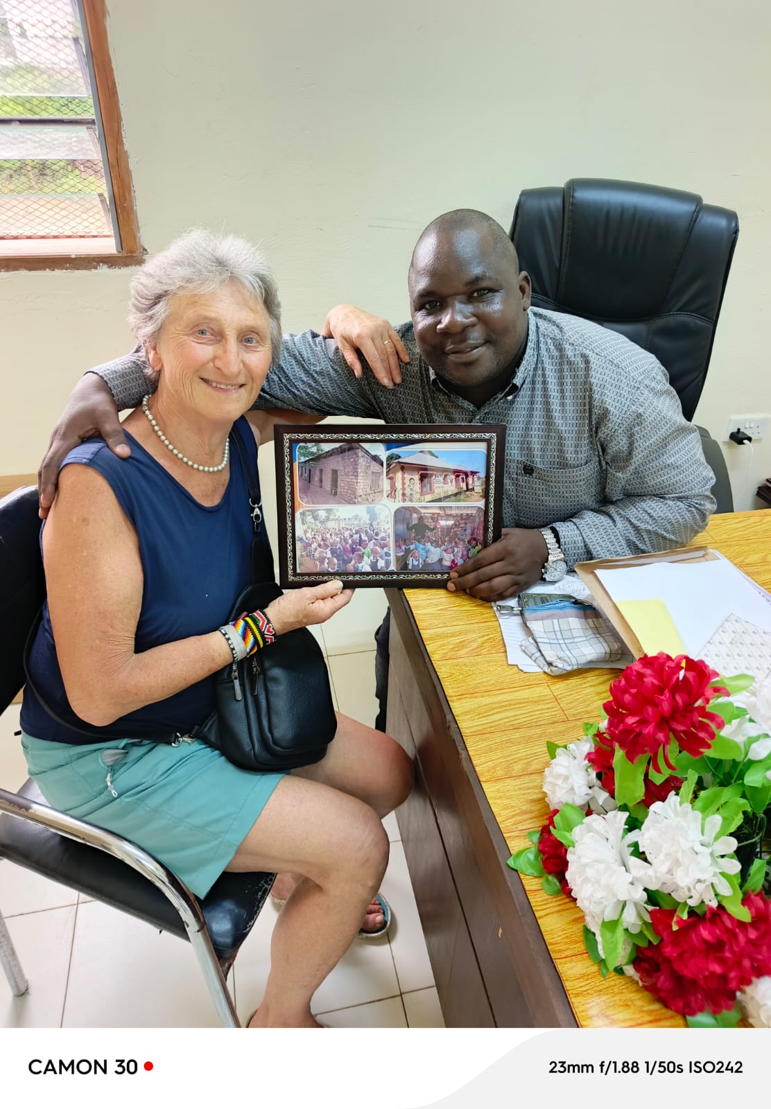 Rosemarie Pscheid and Director Johnstone Mdavan Maelo with a framed photo, alternate pose