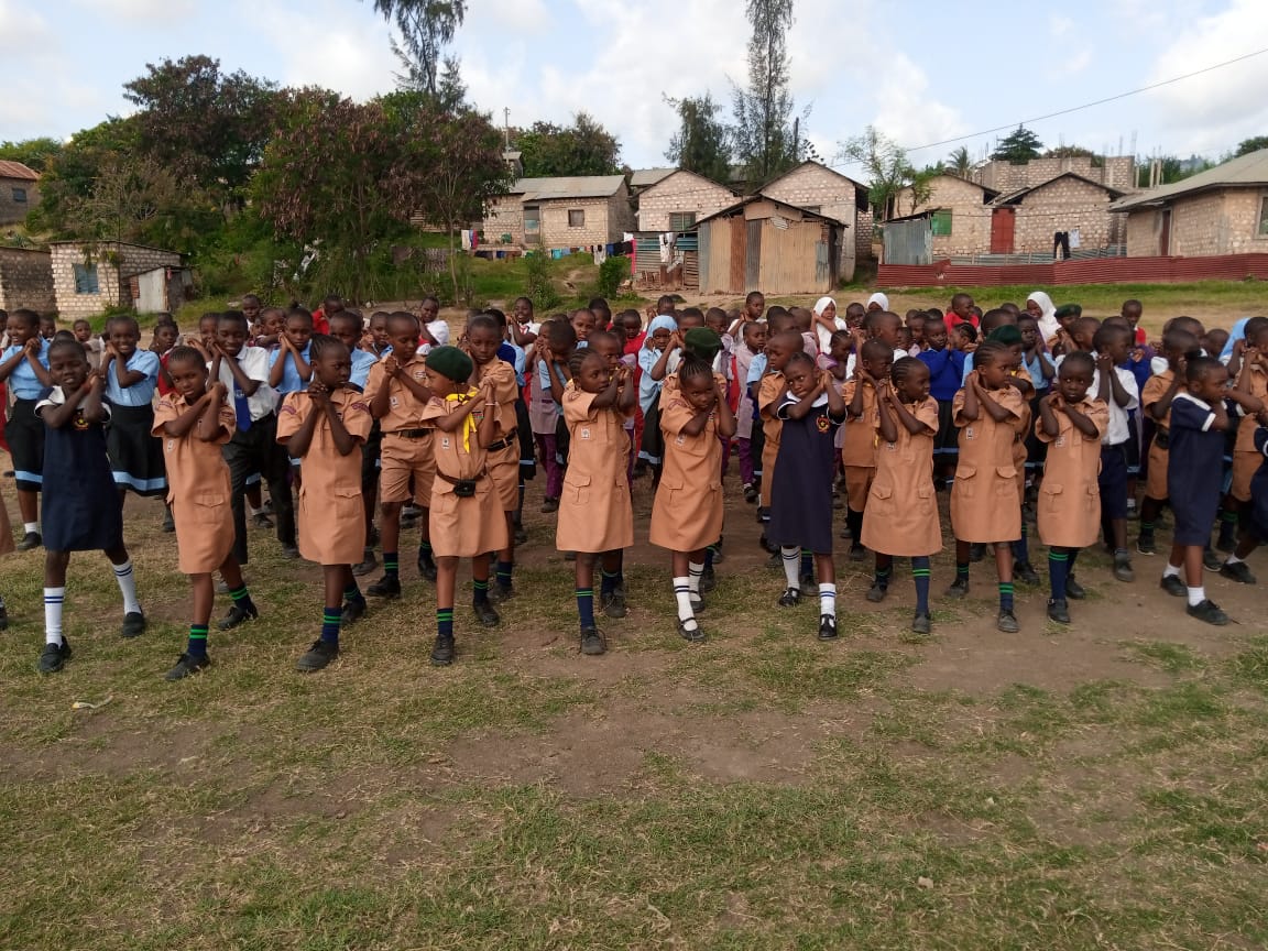 Pupils in khaki scout uniforms performing a drill salute at a scouts rally
