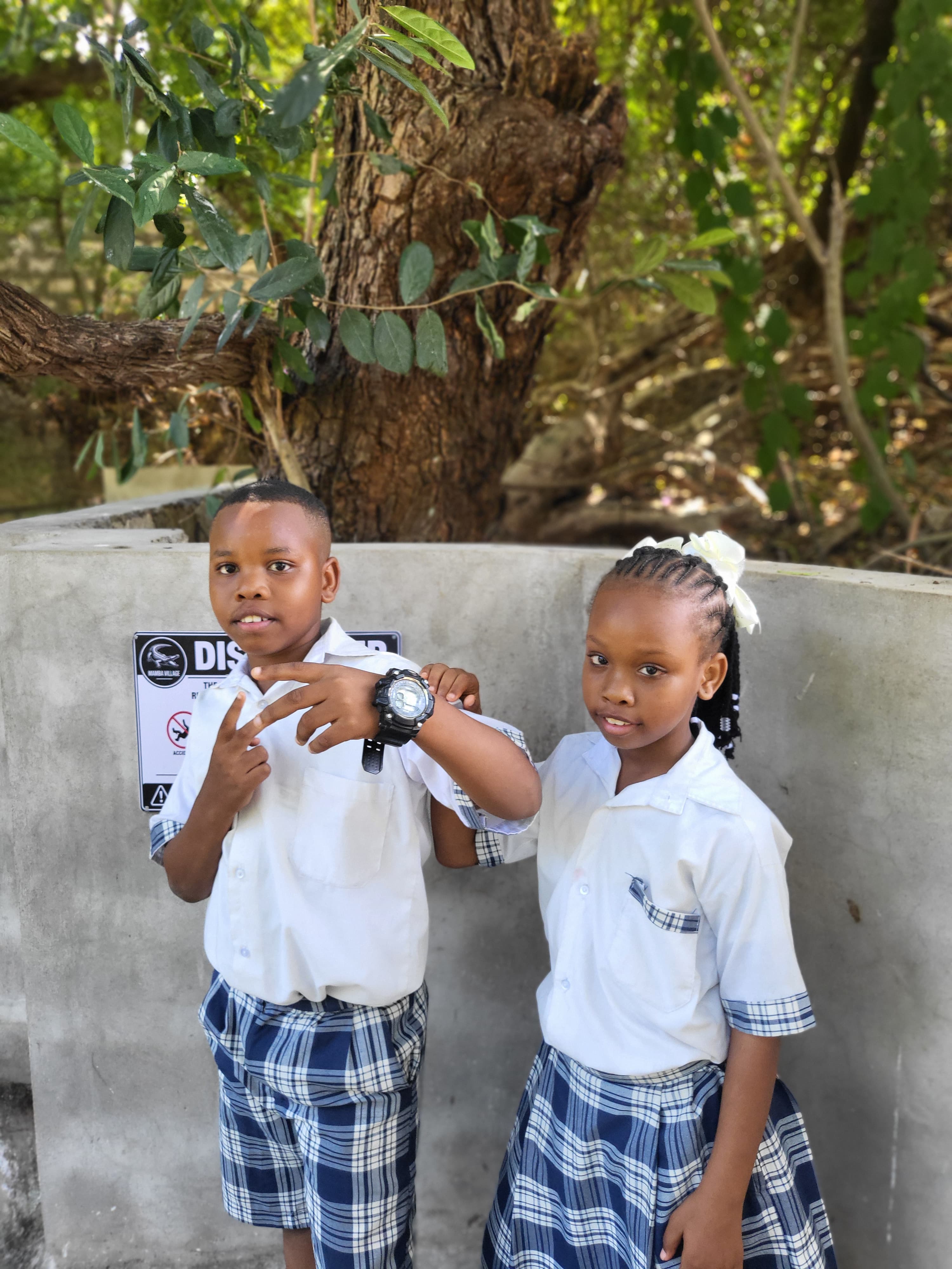 Two students posing by a Discover warning sign at Mamba Village
