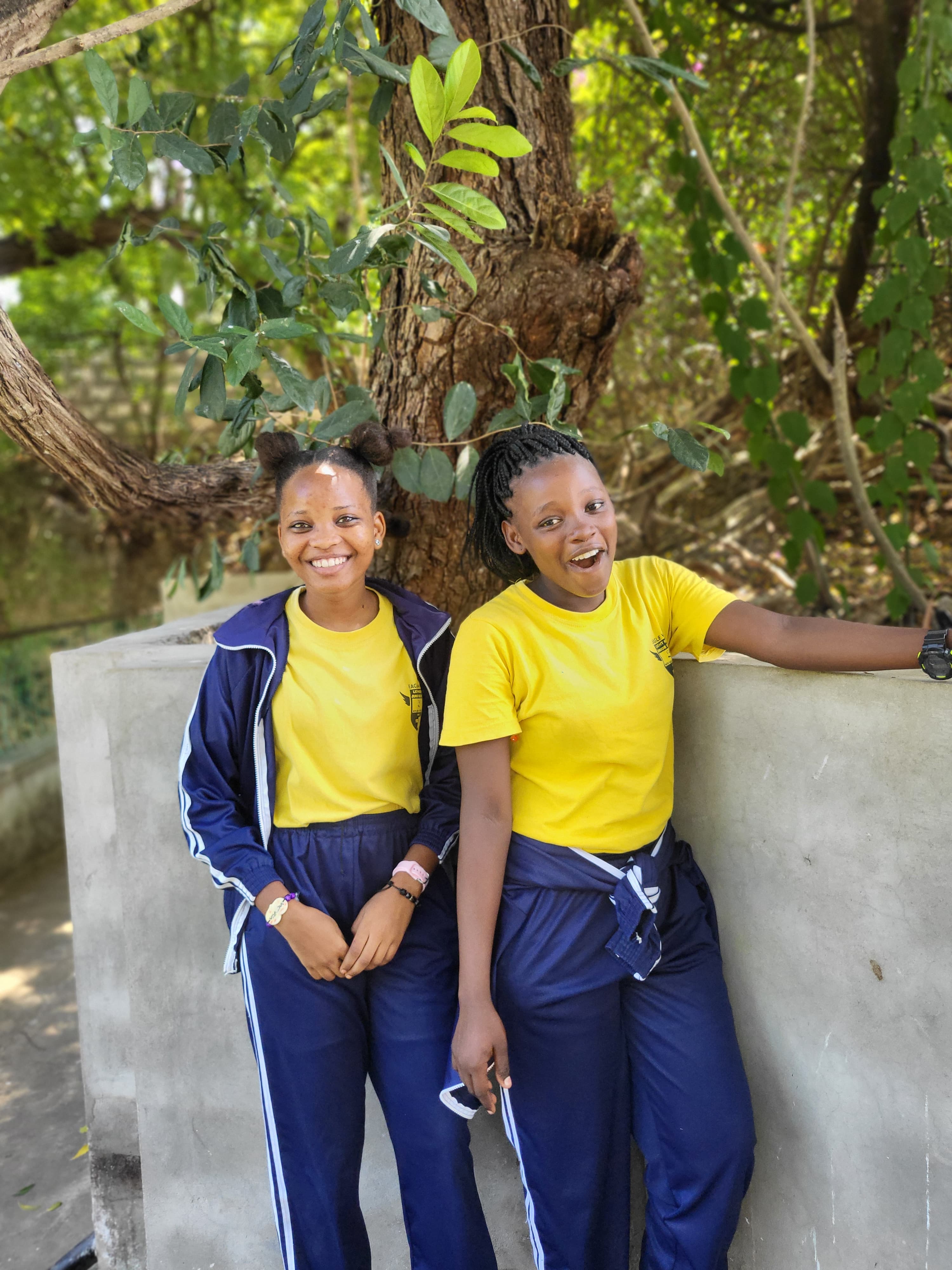 Two students in matching yellow t-shirts laughing during the school trip